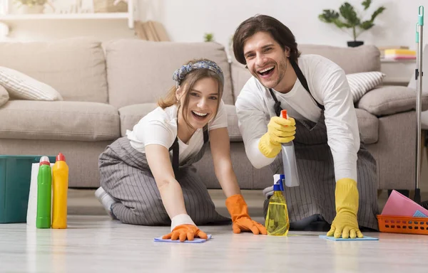 Joven pareja feliz en guantes de goma limpiando piso en su apartamento —  Fotos de Stock