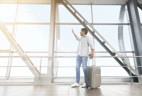 Man Traveler Walking With Luggage In Airport, And Waving To Window — стокове фото