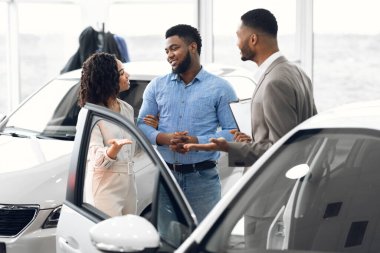 Wife And Dealer Convincing Man To Buy Automobile In Dealership