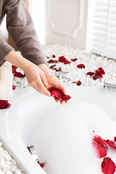 Recadré de femme faisant bain mousseux avec des pétales de rose — Photo