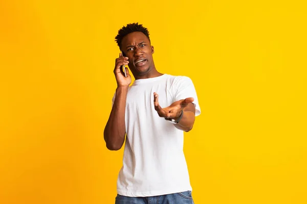 Angry african guy talking on phone, gesturing and shocked — Stok fotoğraf