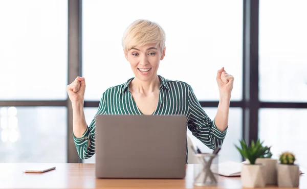 Веселая деловая леди пожимает кулаки, празднуя успех в современном офисе — стоковое фото