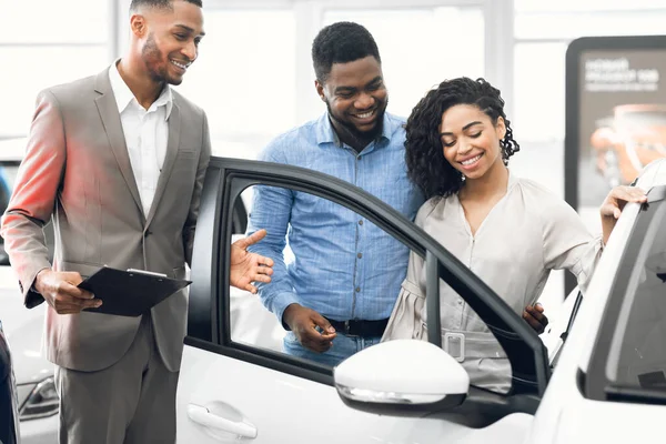 Car Selling Manager Showing Luxury Car To Buyers In Dealership — Stock Photo, Image