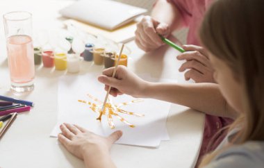 Little girl and her grandmother painting together at table, closeup view
