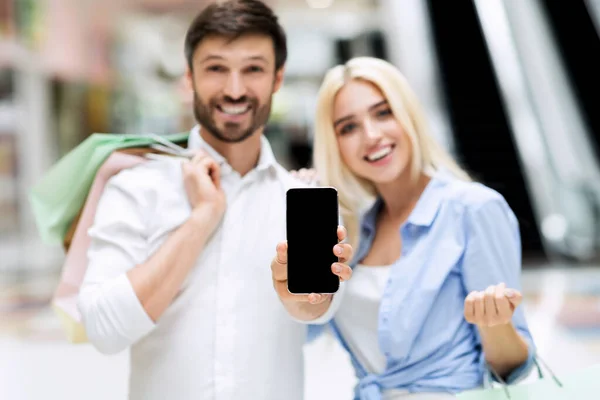 Сімейна пара показує порожній екран смартфона стоїть в магазині — стокове фото