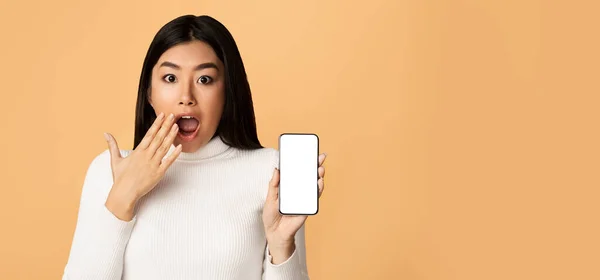 Shocked Asian Woman Showing Smartphone Empty Screen, Beige Background, Mockup — Stockfoto