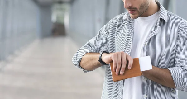 Homem irreconhecível segurando passaporte e bilhetes e verificando o tempo no relógio de pulso — Fotografia de Stock