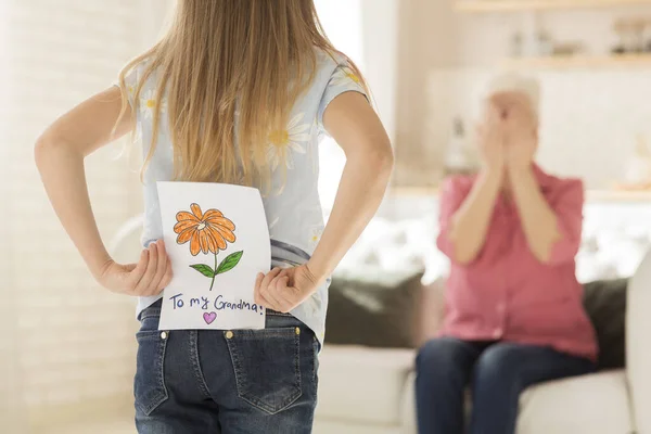 Niña con tarjeta de felicitación para la abuela a sus espaldas, primer plano. Espacio vacío — Foto de Stock