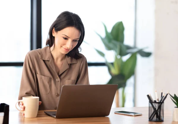 Portrait of smiling woman working on laptop remotely — Stockfoto