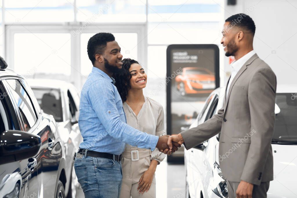 Car Dealer Handshaking With Buyers After Successful Deal In Store