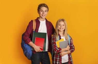 School Education. Brother and sister with backpacks and notepads, yellow background