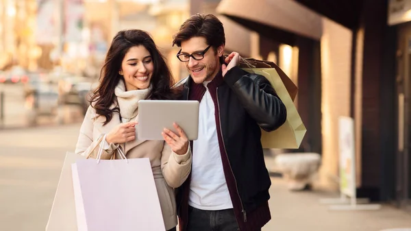 Schönes Paar benutzt Tablet und geht durch die Straßen — Stockfoto