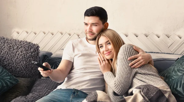 Vonzó fiatal nő és jóképű férfi néz TV-t és ölelés otthon, panoráma — Stock Fotó