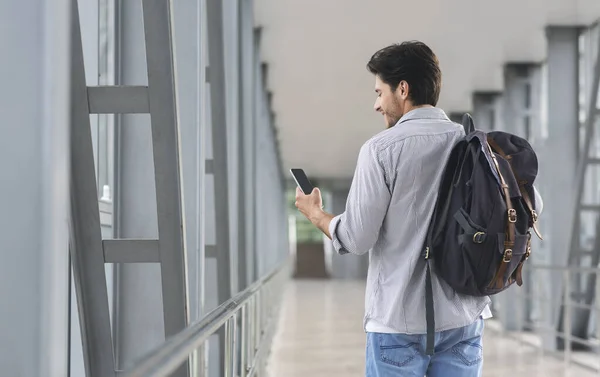 Réservation Hôtel en ligne. Homme tenant un sac à dos et utilisant un smartphone à l'aéroport — Photo