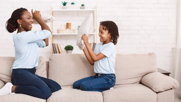 Black mother and daughter having pillow fight — Stockfoto