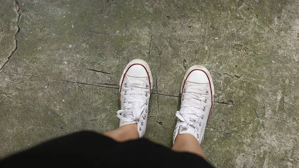 Дівчина в модних кросівках, що стоять на асфальтній дорозі, вид зверху. Простір для тексту — стокове фото