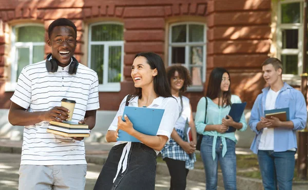 Życie uniwersyteckie. Wesoła para studentów rozmawia i śmieje się razem na dworze. — Zdjęcie stockowe