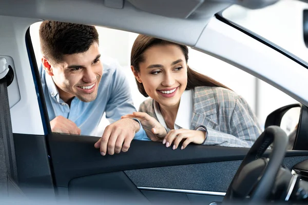 Esposo y esposa eligiendo un nuevo auto juntos en la tienda de concesionarios — Foto de Stock