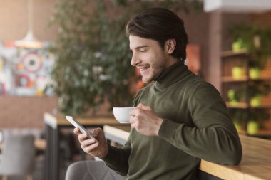 Kafede kahve molası veren başarılı bir işadamı, akıllı telefon kullanıyor.
