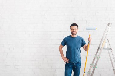 Mutlu adam yeni tuğla duvarları boyamaya hazırlanıyor.