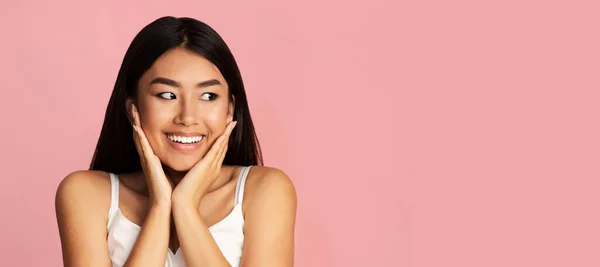 Happy Girl Cupping arc a kezében keres félre, rózsaszín háttér — Stock Fotó