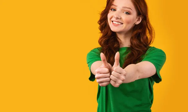 Leende flicka Gesturing tummen upp Godkänna något stående över gul bakgrund — Stockfoto