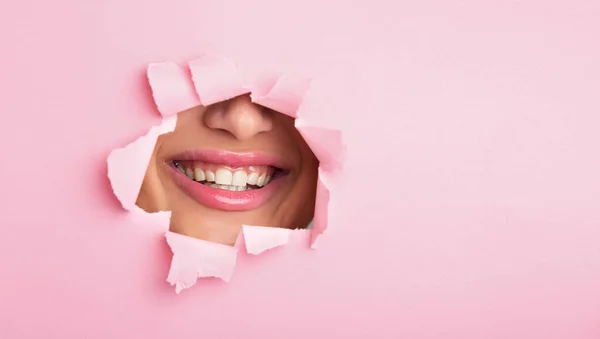 Kvinna som visar läppar ur rosa pappershål — Stockfoto