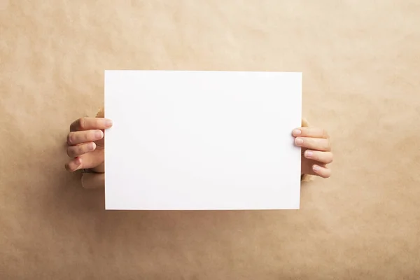 Módní nápad. Dívka prezentující bílý prázdný list s prostorem pro design mezerou v řemeslném papíru — Stock fotografie