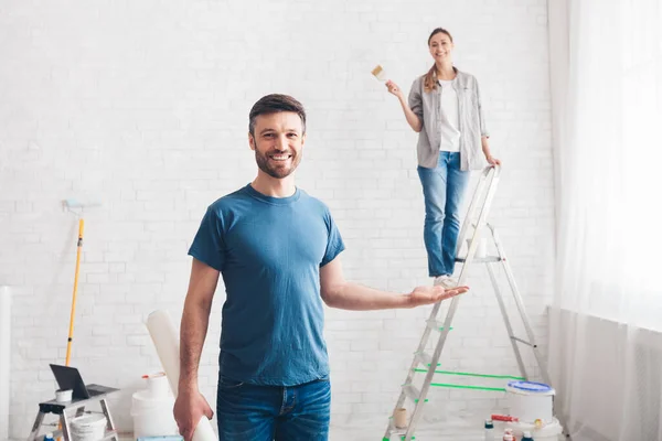 Man holding wife on palm while she painting walls — Stock Photo, Image