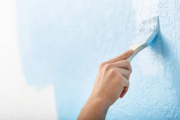 Mężczyzna ręka z farbami pędzelkowymi na teksturowanej ścianie — Zdjęcie stockowe