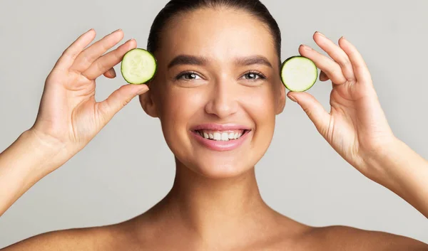 Joven mujer juguetona sosteniendo trozos de pepino — Foto de Stock