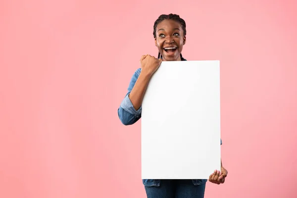 Mujer emocionada sosteniendo tablero blanco de pie sobre fondo rosa, burla — Foto de Stock