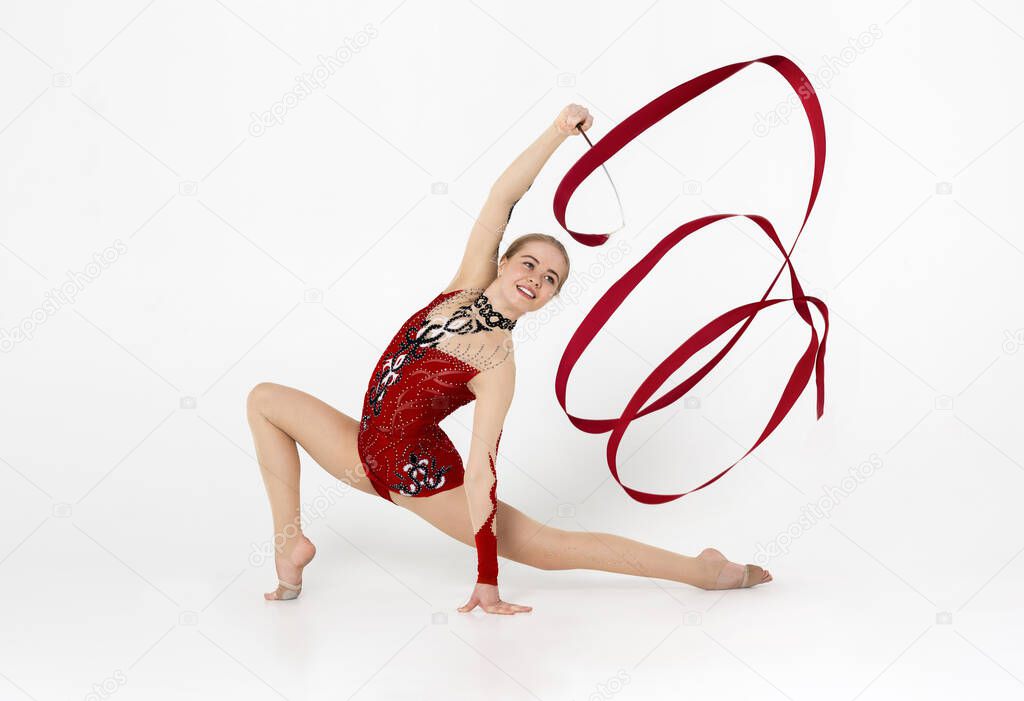 Skilled gymnast in beautiful red leotard performing with string on white background