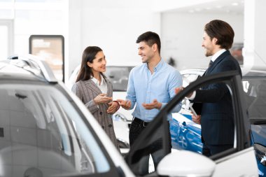Dealer Showing Couple New Auto In Dealership Store