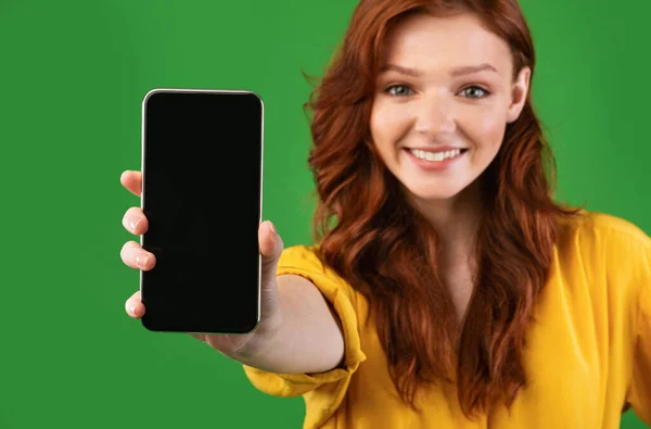 スマートフォンのブランク画面広告アプリケーションを表示する女の子,緑の背景 — ストック写真