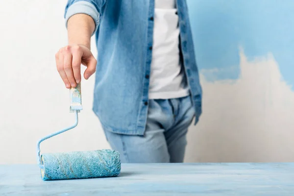 Guy in jeans paints with roller in blue color — Φωτογραφία Αρχείου