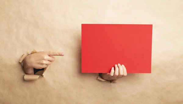 Señora apuntando a la hoja roja vacía a través del hueco en papel kraft, espacio en blanco para el diseño — Foto de Stock