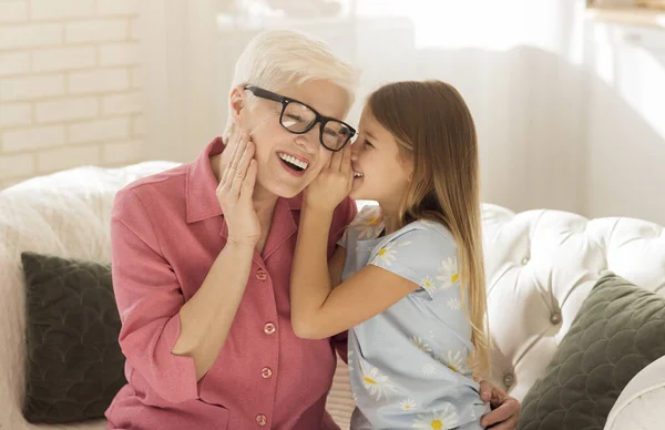 Little girl sharing secrets with her granny at home — Stock Photo, Image