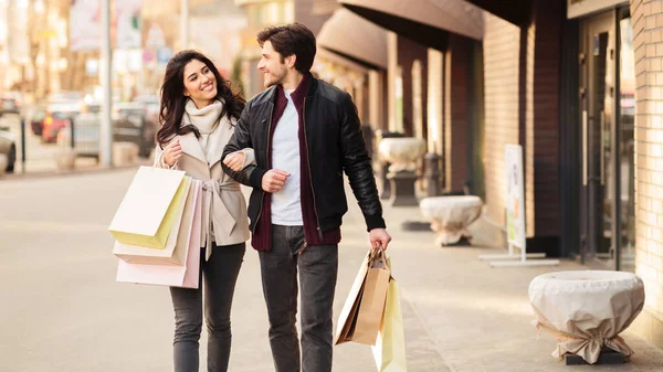 Joven pareja amorosa caminando llevando bolsas de compras —  Fotos de Stock