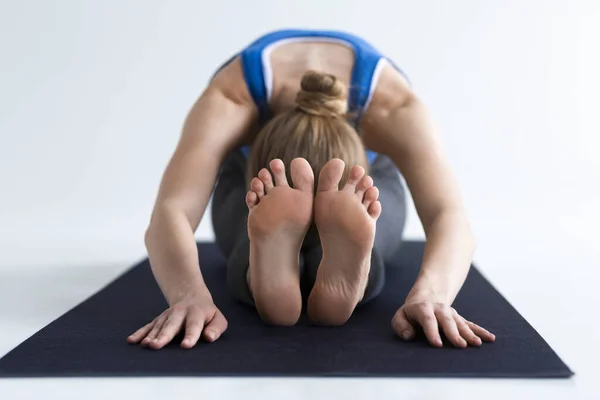 Young gymnast doing her stretching or yoga exercises on white background — 스톡 사진