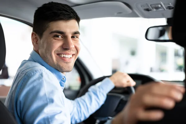 Jovem feliz sentado em automóvel no centro de concessionárias — Fotografia de Stock