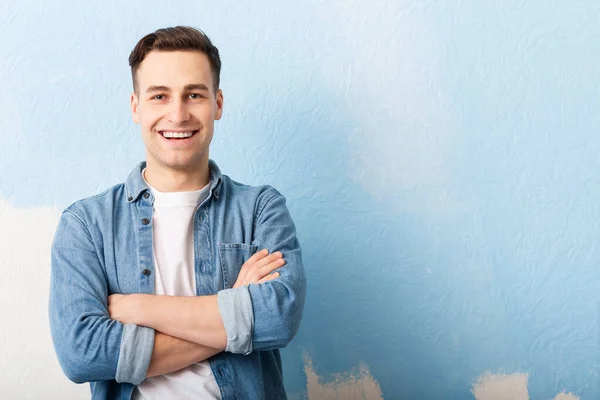 Усміхнений хлопець на фоні незакінченої синьої стіни — стокове фото