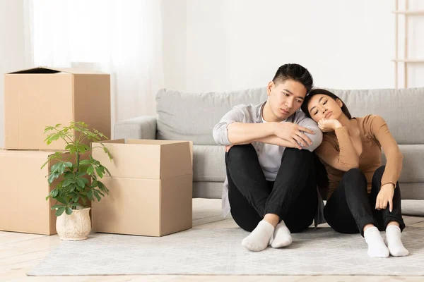 Unhappy asian man and woman sitting on the floor — Stockfoto