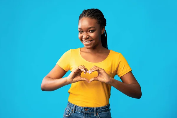 Μαύρο κορίτσι χειρονομώντας σχήμα καρδιάς στέκεται σε μπλε φόντο — Φωτογραφία Αρχείου