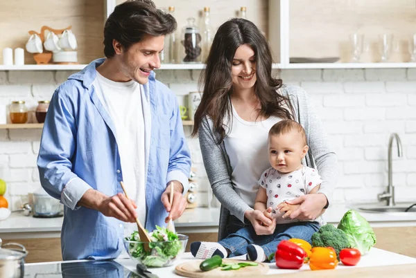 Bebeğin annesi ve babası mutfakta organik sağlıklı öğle yemeği pişiriyor. — Stok fotoğraf