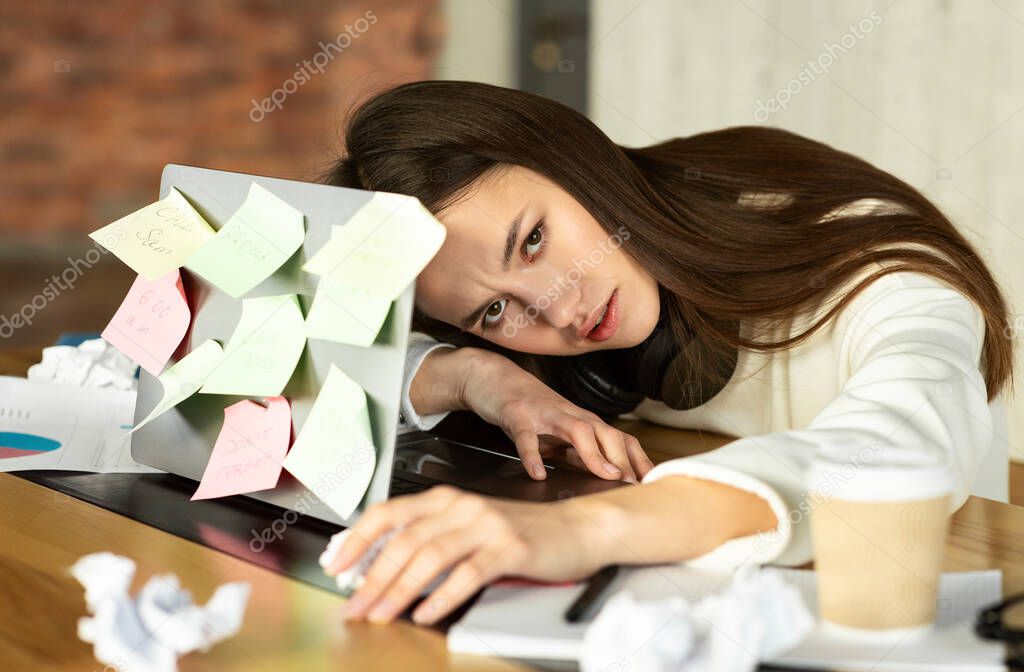 Overwork concept. Sad girl lying on laptop