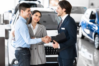Car Dealer Shaking Hands With Buyers After Successful Deal
