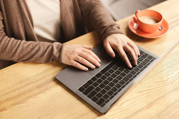 Kvinne som nyter kaffe og jobber med laptop på kafe – stockfoto