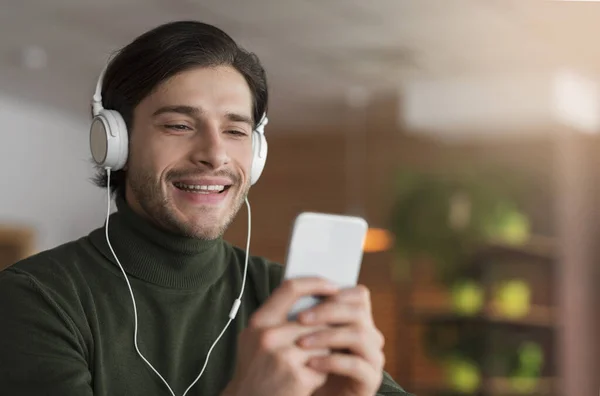 Cara alegre no fone de ouvido ter chamada de vídeo, usando telefone — Fotografia de Stock