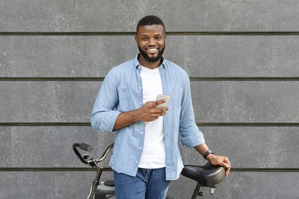 Retrato ao ar livre de cara afro bonito com smartphone e bicicleta — Fotografia de Stock